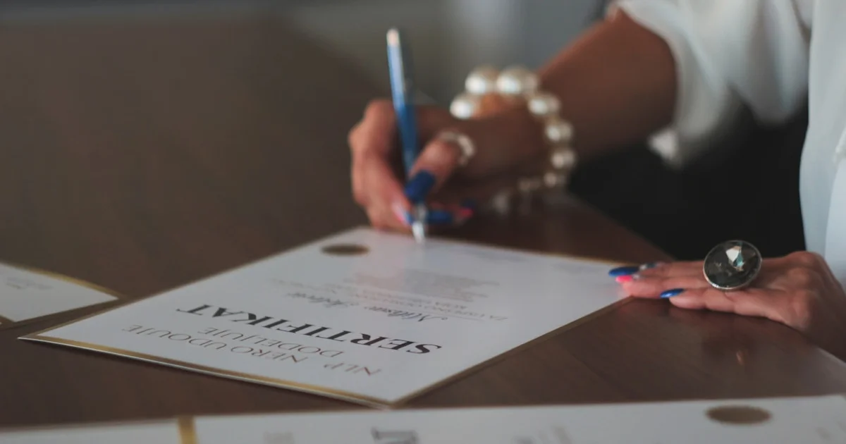 Mujer escribiendo con bolígrafo en un documento sobre mesa
